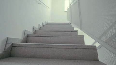Climbing the white stairs. Someone step by step climbs the steps POV. Climb up the stairs, passing one floor after another in the hotel. Modern interior, white walls, stairs are covered with tiles
