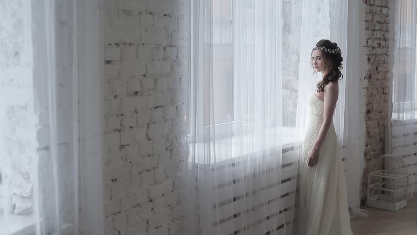 Brunette bride in fashion white wedding dress with makeup. Wedding day of bride in bridal gown. Beauty woman in veil. Fashion brunette model indoors. Beauty portrait of model in white bridal dress