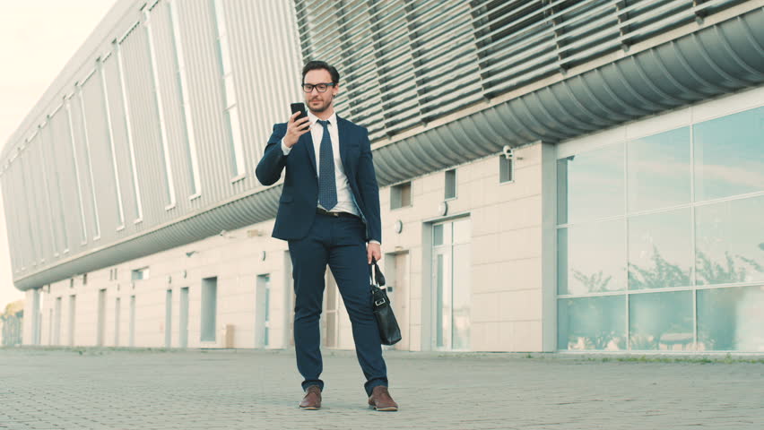 Happy stylish businessman hear good news on the phone and jumping with happy emotions outdoors near office building. Royalty-Free Stock Footage #27770332
