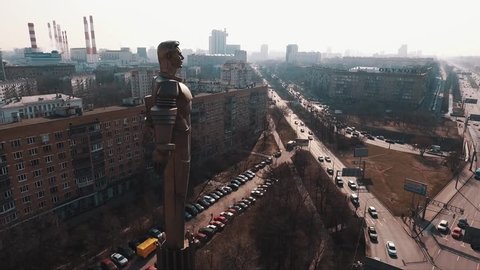 Drone flight around Yuri Gagarin metal monument on road rush traffic crossroad in city dormitory area under clear blue sky on summer sunny day