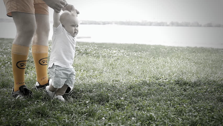 Baby with father playing with soccer ball on the grass