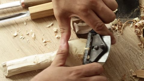 Man cuts a spoon whith a spokeshave. Closeup