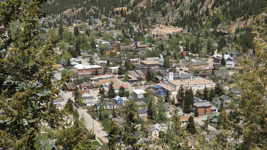 Establishing shot-Historic Georgetown Colorado high angle view looking down on town with blowing pine trees framing the scene