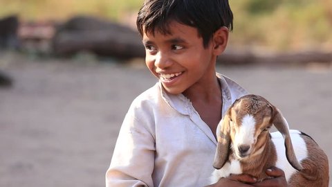 MANDU, INDIA - FEBRUARY 03, 2017 : Unidentified Indian boy on the street with goatling. Poverty is a major issue in India