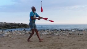 Juggler using juggling pins to practice at the beach in Sicily - Slow motion video from a drone