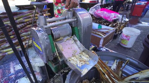 Labuan,Malaysia-June 8,2017:Sugar cane juice with cut pieces cane ready to crush sugar cane machine & making the juice in Labuan,Malaysia.Its an extremely common street drink in Asean