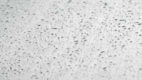 Raindrops falling on car windshield glass