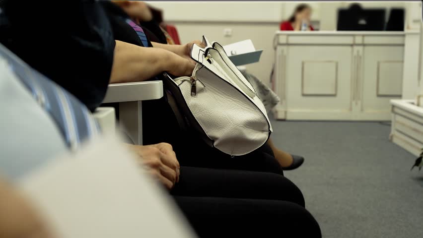 senior women sit with documents in hands waiting in queue at official department office reception