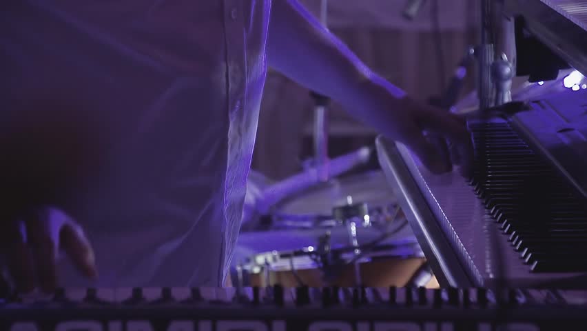 Keyboardist plays on several musical instruments at a concert as part of a musical group. Close up. 