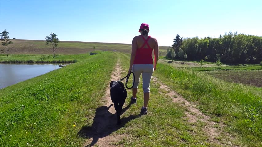 A woman with black dog walk in nature.