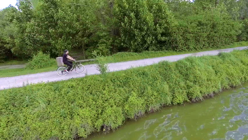 A young man is enjoying the ride with a bicycle around the lake and he is also looking around.