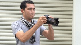 Handsome young man holding a DSLR with shooting video on metal sheet background