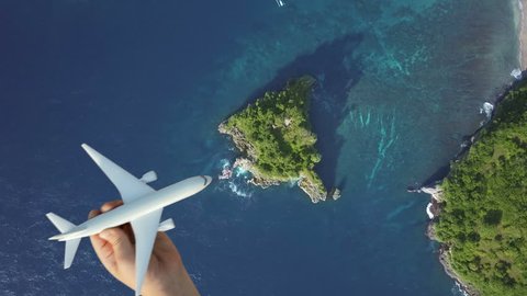 Travel around the world by air transport, summer vacation concept on nature landscape, blue lagoon background. Scenic aerial view of child hand playing plane, flying above azure water of ocean, island Adlı Stok Video