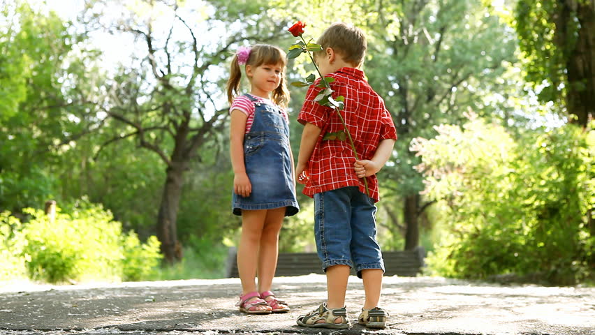 Two childrent speaking and boy present flower