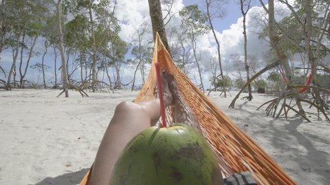 First person view of beautiful girl drinking coconuts milk laying on a hammock in a mangrove forest in Jericoacoara, Brazil