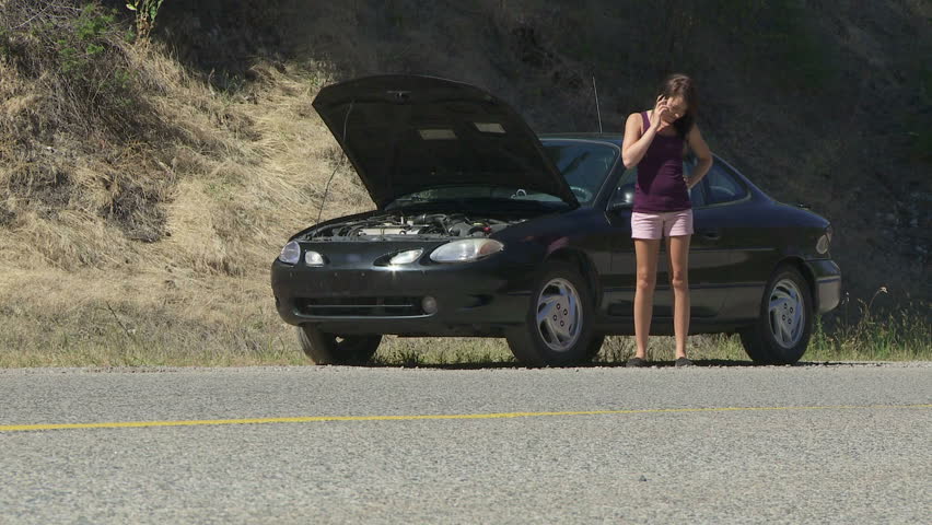 Young woman experiencing car trouble and calling for assistance on her cell