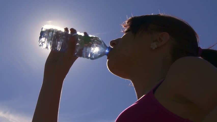 Young woman drinking water after a fitness run
