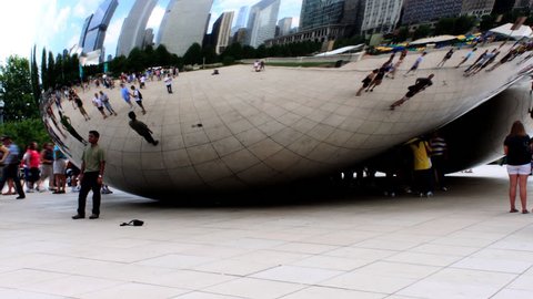 CHICAGO - AUGUST 2009: A motion time-lapse of Chicago buildings and cumulus clouds reflecting in the Millennium Park bean with people looking at their reflection