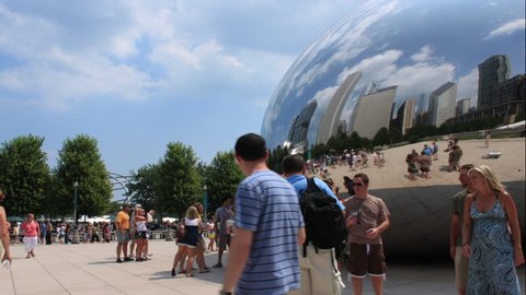 CHICAGO - AUGUST 2009: A motion time-lapse of Chicago buildings and cumulus clouds reflecting in the Millennium Park bean with people