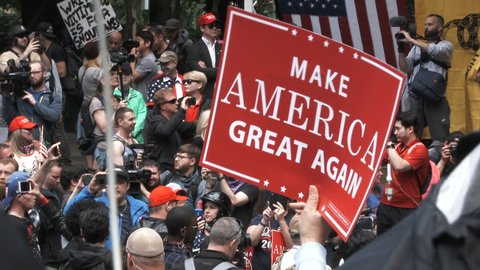 JUNE 4TH, 2017 - PORTLAND, OREGON: Donald Trump supporters chant "Lock Her Up" at Trump rally with person holding "Make America Great Again" sign.