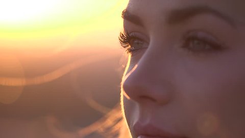 Closeup of woman's face outside at sunrise/sunset. Wide shot, slow motion, handheld