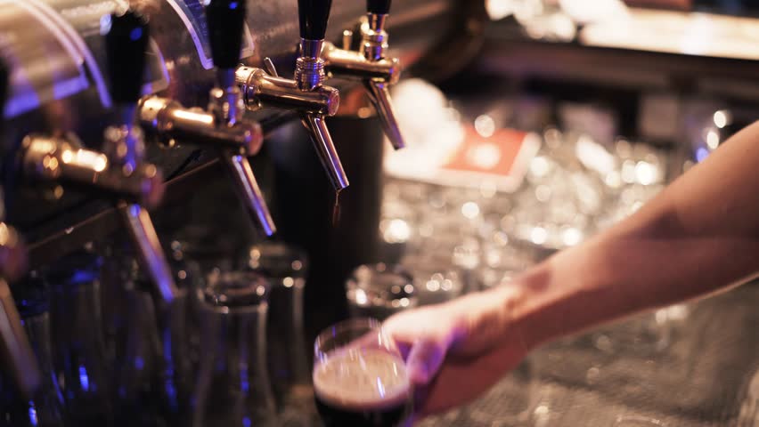 Close up of an unrecognizable young bartender pouring beer into a glass and putting it on a tray. He is ready to deliver. Handheld real time close up shot | Shutterstock HD Video #27834562