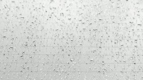 Raindrops falling on car windshield glass