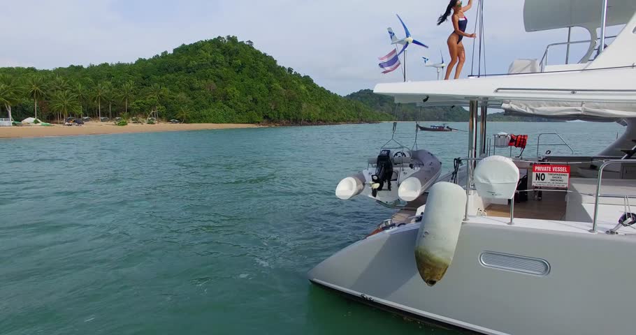 Aerial: Beautiful model posing on the yaht near the beach. Andaman sea. Phuket. Thailand.