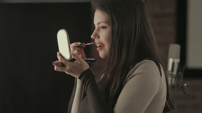 Bautiful young female singer applying lips makeup with cosmetic brush