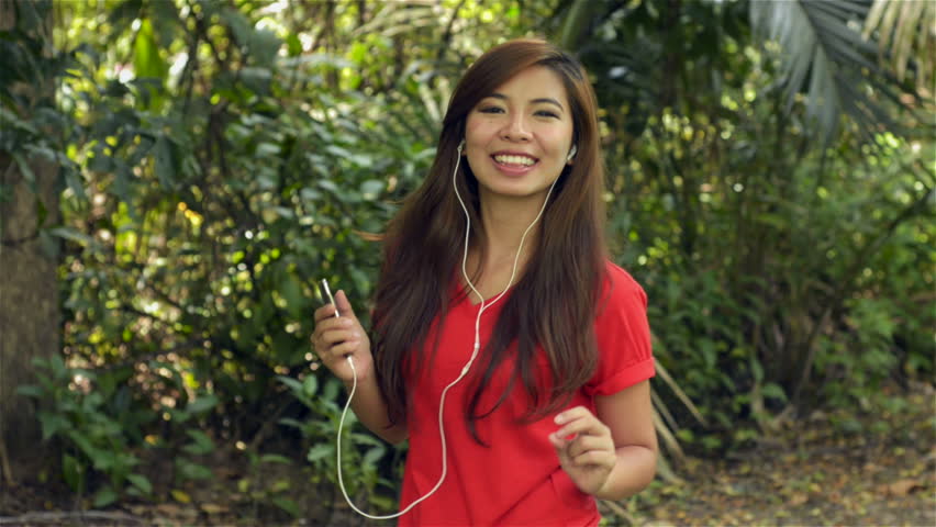 Young asian woman dancing to music on her headphones, turns and smiles at the