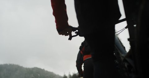 POV low angle of three extreme mountain bikers peddling through fog over rocks in slow motion. Rocks and forest in the background, bike details and pedals in the foreground.