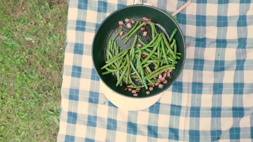 Delicious green beans in frying pan cooking with bacon from above.