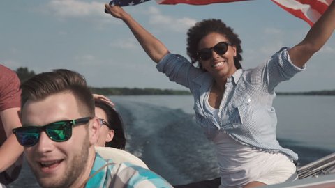 Slowmotion of group of cheerful friends on boat celebrating Independence day and having fun.