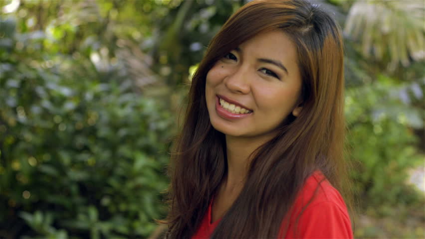 Young Asian woman turning to face the camera, smiling and putting both thumbs