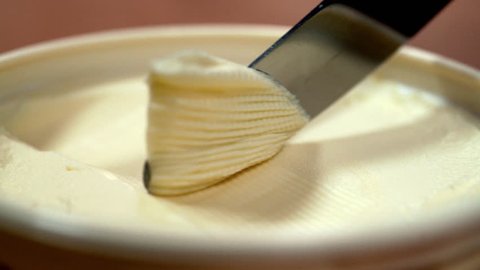 PUTTING KNIFE INTO BUTTER IN THE OPENED BOX. EXTREME CLOSE UP, BLURRED BACKGROUND