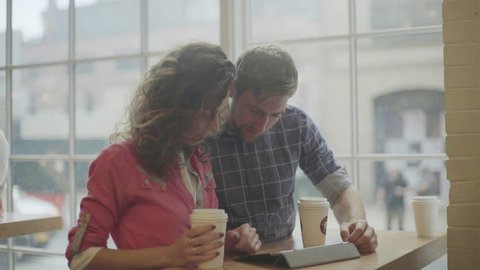 Couple using digital tablet together in coffee shop