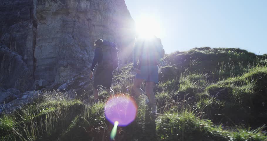 Four friends walking along hiking trail path with sun light flare. Group of friends people summer adventure journey in mountain nature outdoors. Travel exploring Alps. 4k slow motion 60p video Royalty-Free Stock Footage #27869677