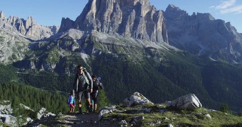 Four friends walking along hiking trail path. Group of friends people summer adventure journey in mountain nature outdoors. Travel exploring Alps, Dolomites, Italy. 4k slow motion 60p video