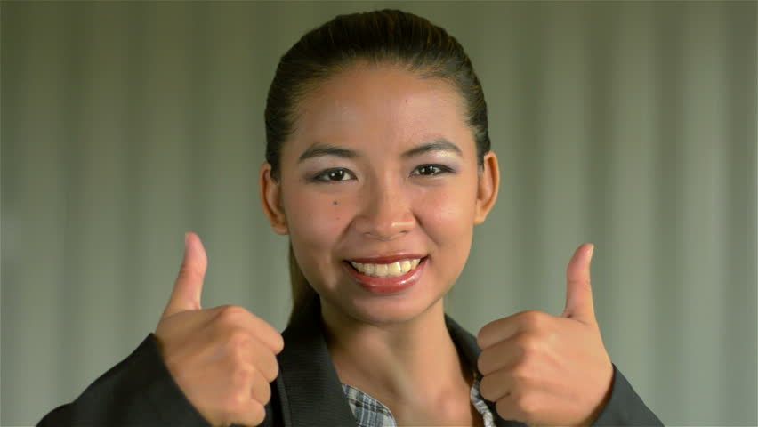 Young Asian businesswoman turning to the camera and giving a double thumbs up