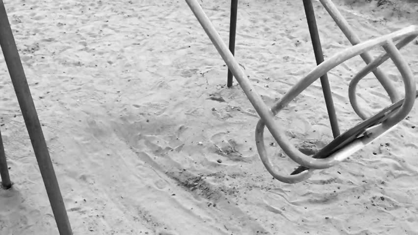 Lonely swing like symbol loneliness and boring. Solitariness empty playground swing on sand. Extreem slow motion black and white BW.