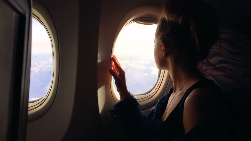 A young girl travels by plane and sits by the window and enjoys the view and then closes the porthole. 1080p Royalty-Free Stock Footage #27882865
