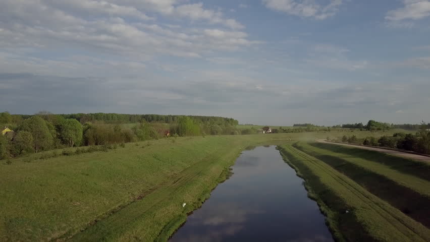 A young mother with her daughter and son is walking on a bridge near a river. Happy family outdoors in summer. Beautiful landscape. Aerial shot. 4K footage. 