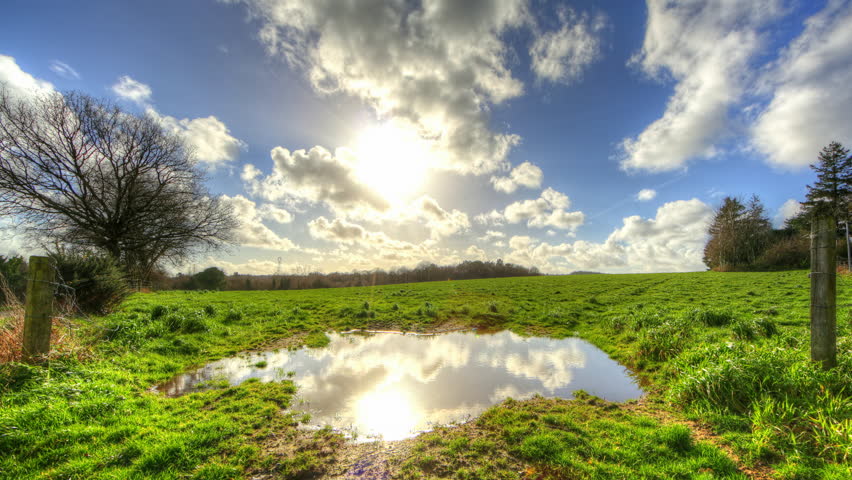 Clouds reflecting in water pond in grass fields, 4K motion time lapse clip, High Dynamic Range Imaging
