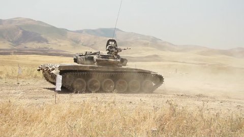 The tank fires on the enemy in a desert area in Syria, closer to the border with Iraq. Tank-T72 on the field is shooting at the terrorists ISIS and DAESH. The video is shot by a military journalist