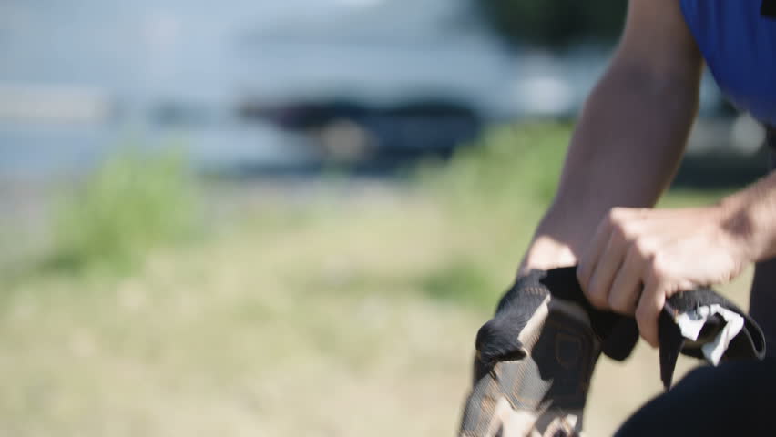 Tight angle detail shot of a whitewater kayaking putting on his gloves while gearing up to paddle down whitewater rapids in Patagonia, Chile. Exterior daytime realtime shot.