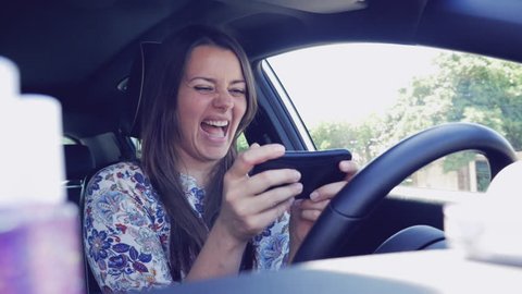 Woman texting message with cell phone while driving car doing selfie slow motion