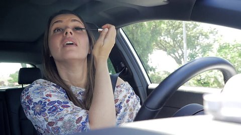 Woman driving while putting makeup not looking road distracted