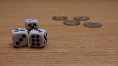 Close up of coins and white dices on wooden background