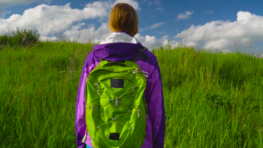 Woman enjoys hiking with a backpack over hilly terrain. Hiking