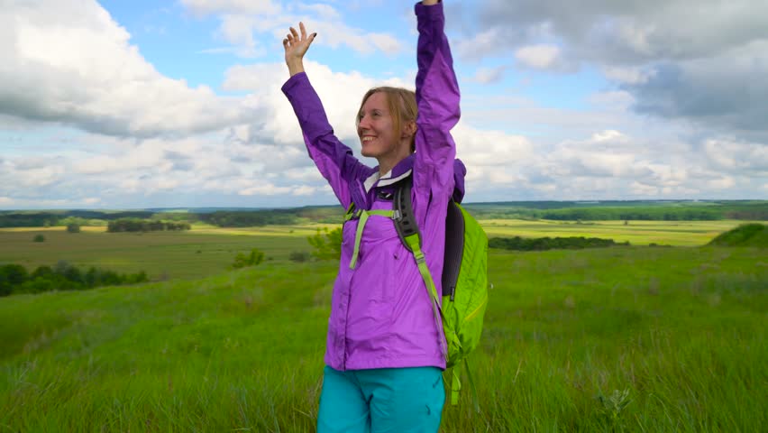 Woman enjoys hiking with a backpack over hilly terrain. Hiking